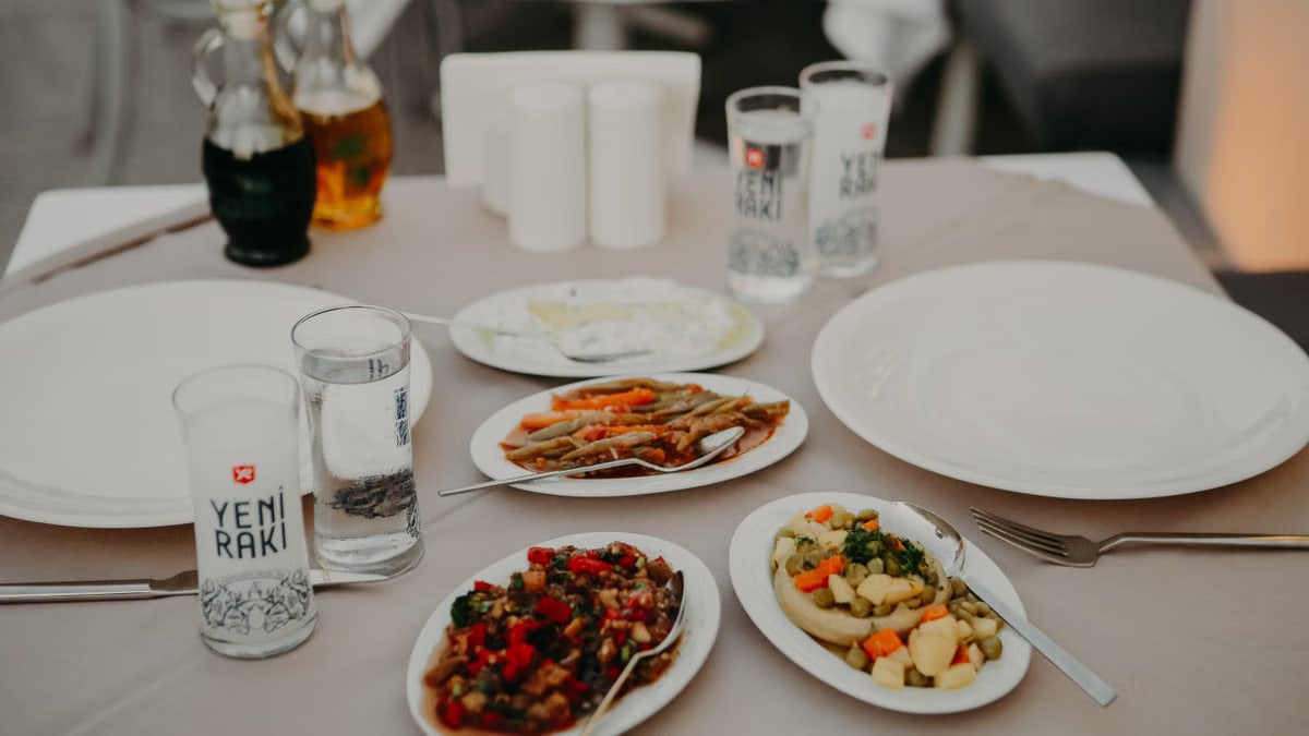 From above of served table with assorted delicious appetizers with beverages and dishware on veranda of restaurant in evening