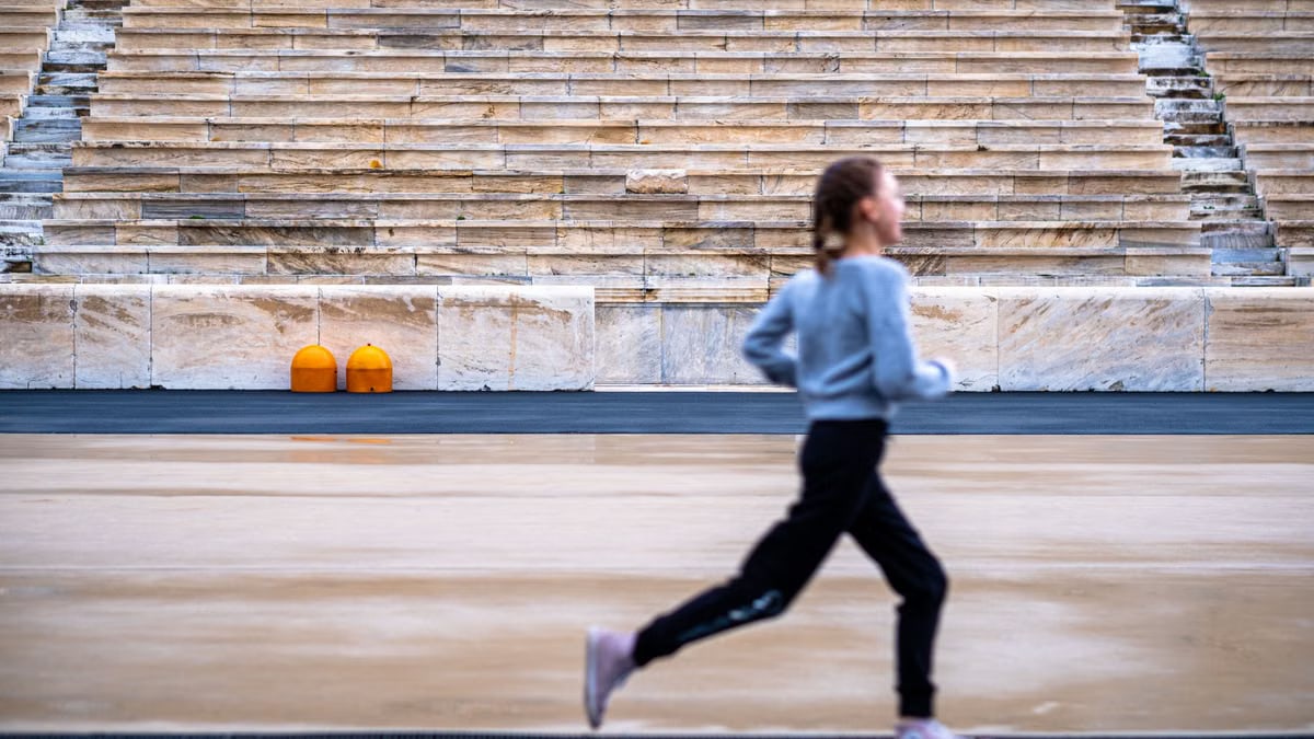 A girl runs in a historic stadium with empty stands, symbolizing youthful energy and ancient architecture.