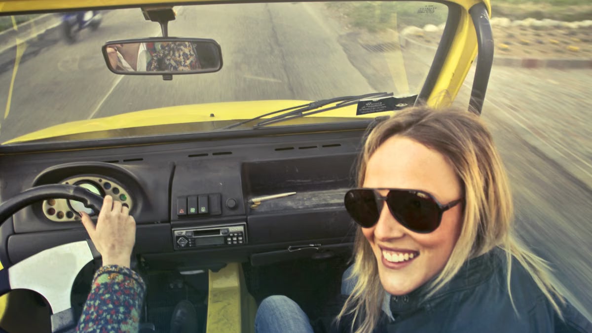 Happy woman wearing sunglasses in a convertible, enjoying a sunny day drive.